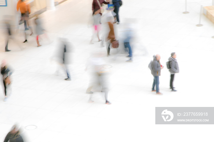 Blur of people moving around on white floor.