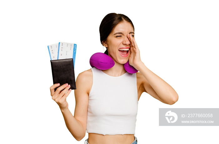 Young caucasian woman with inflatable travel pillow holding a passport isolated shouting and holding palm near opened mouth.