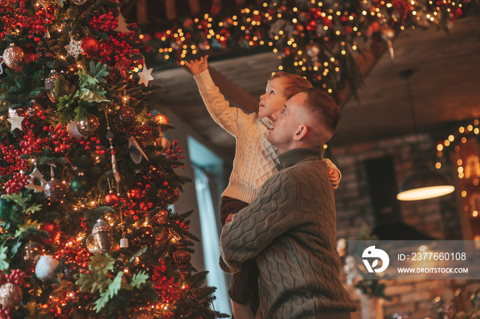 Candid authentic happy dad playing with little son fooling around at wooden lodge Xmas decorated