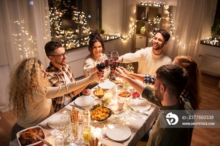 holidays, celebration and people concept - happy friends having christmas dinner at home drinking non-alcoholic red wine