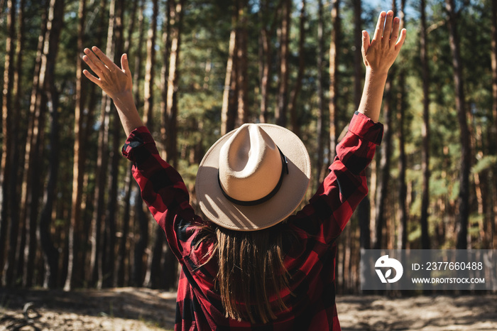 Woman with hat and red plaid shirt in the forest