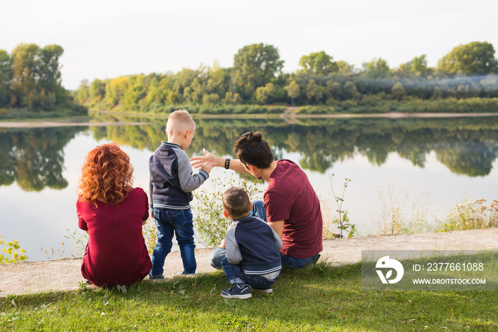 Children, parenthood and nature concept - Big family sitting on the grass