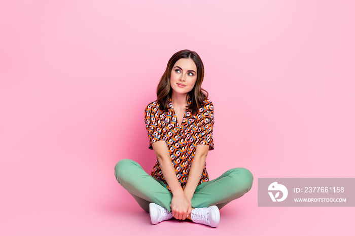 Full length portrait of positive minded creative person sit floor look empty space isolated on pink color background