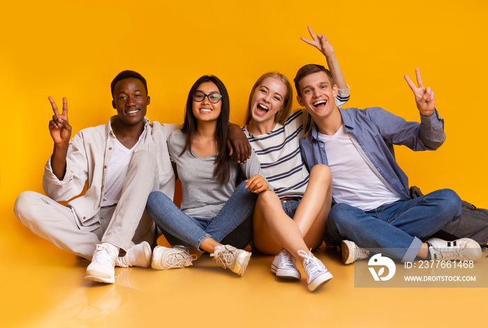 Happy students having fun over yellow studio background