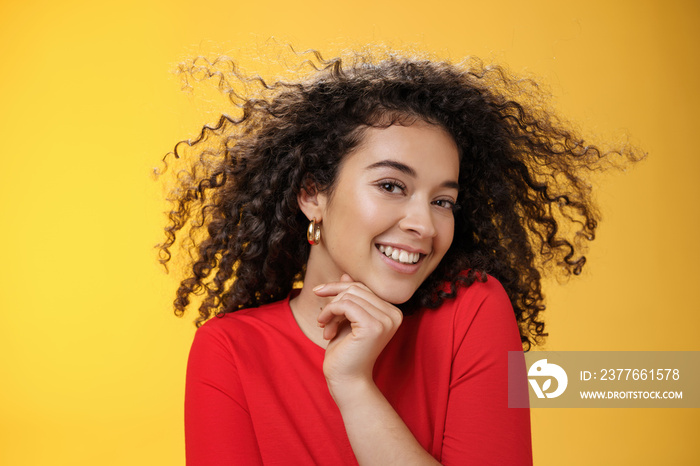 Romance, women and beauty concept. Portrait of tender and gentle pretty woman with curly hair flying in air as she turning head and smiling sensually, flirting with camera touching chin