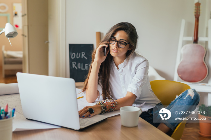 Running her business from home.young woman using mobile phone in her home office