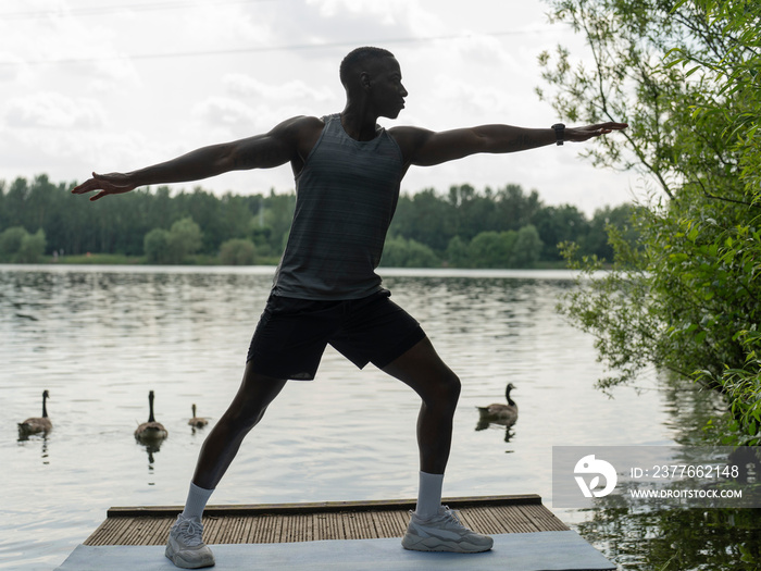 Man practicing yoga by lake