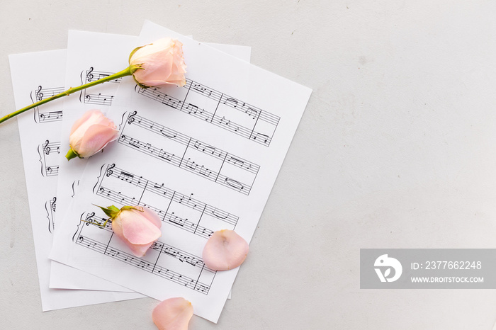 Music sheets and flowers on light background