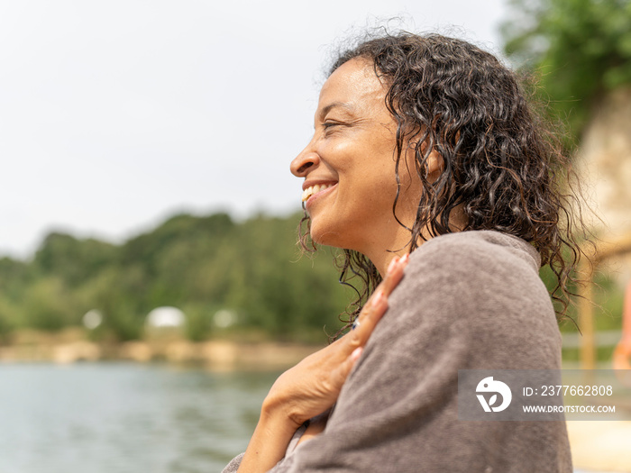 Portrait of smiling woman wrapped in towel by lake