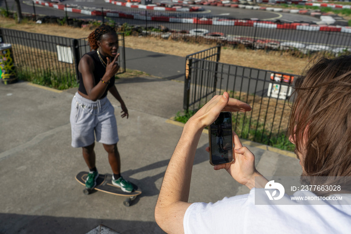 Man photographing female friend on skateboard