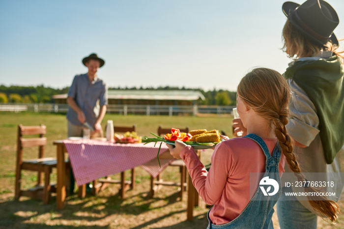 Mother and daughter carrying vegetables to table