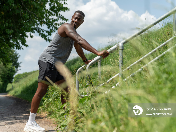 Man stretching against railing in park