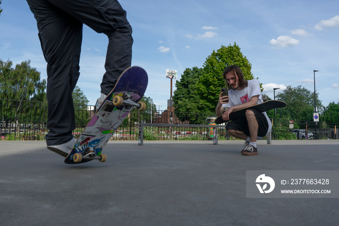 Man recording friend doing skateboard tricks