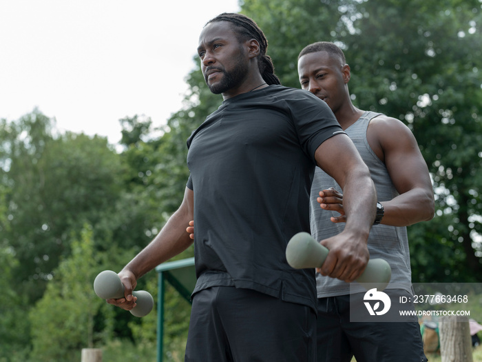 Two men exercising with dumbbells in park