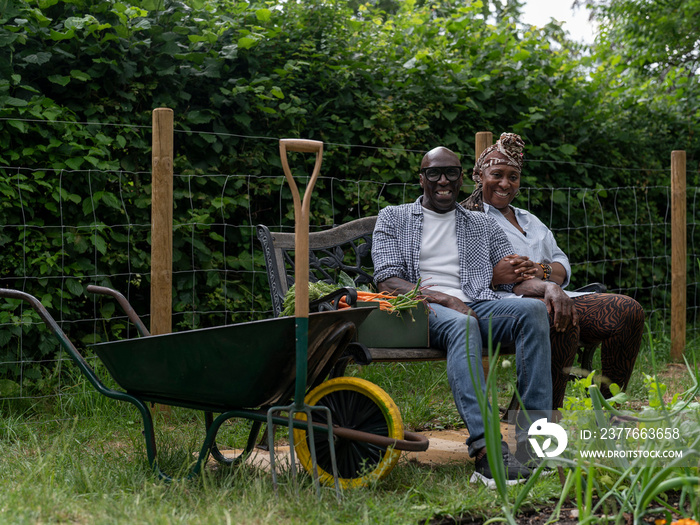 Portrait of smiling couple resting on bench after working in garden