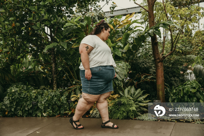 plus size woman walks through garden of tropical plants