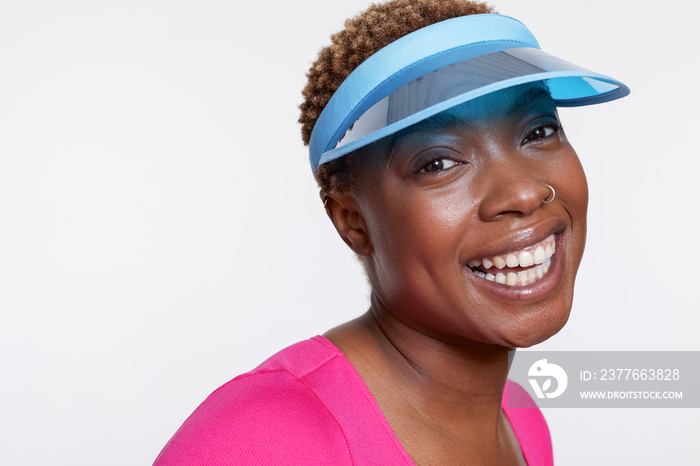 Studio portrait of smiling woman wearing blue sun visor