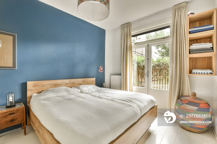 a bedroom with blue walls and white flooring, wooden headboards and a bed in front of a window