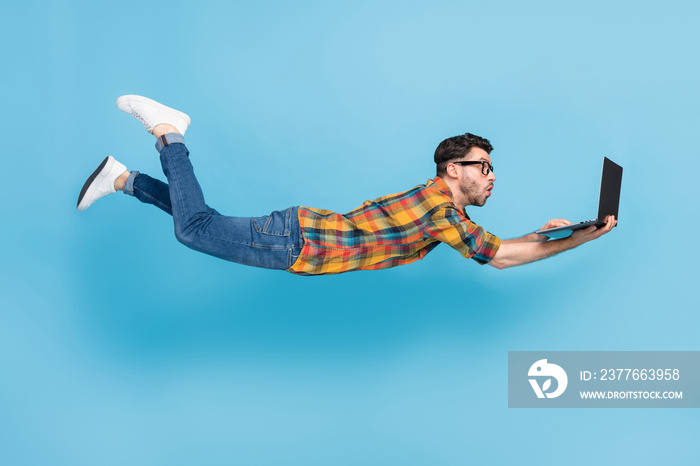 Full body profile photo of impressed guy fly fall hold wireless netbook isolated on blue color background