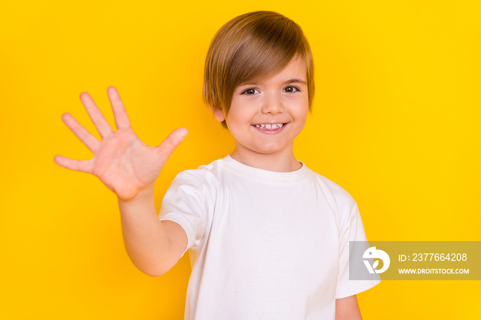 Portrait of attractive lucky cheerful pre-teen boy giving five fingers good result isolated over bright yellow color background