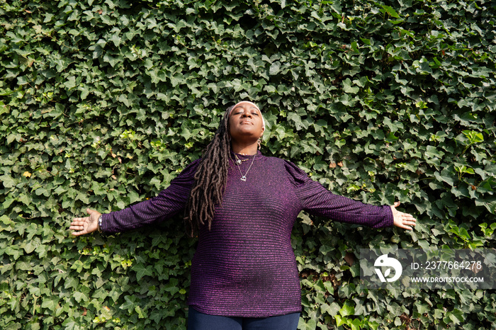 Portrait of beautiful woman with dreadlocks in front of ivy wall