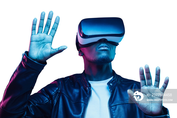 African man playing video game with virtual reality headset, trying to touch something with hands in metaverse