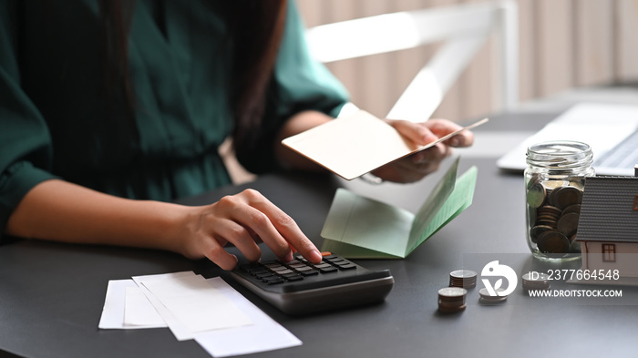 Closeup female calculate saving money on home table.