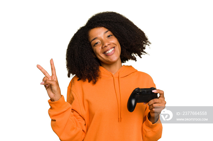 Young African American woman holding a game controller isolated joyful and carefree showing a peace symbol with fingers.