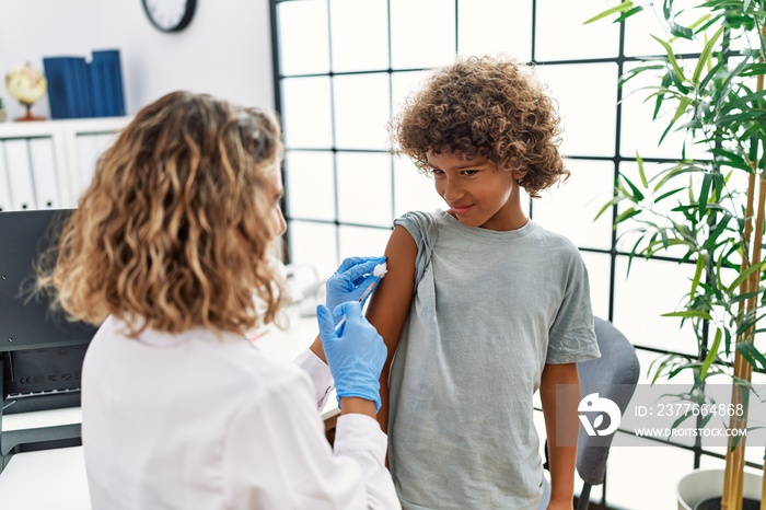 Mother and son wearing doctor uniform vaccinating child at clinic