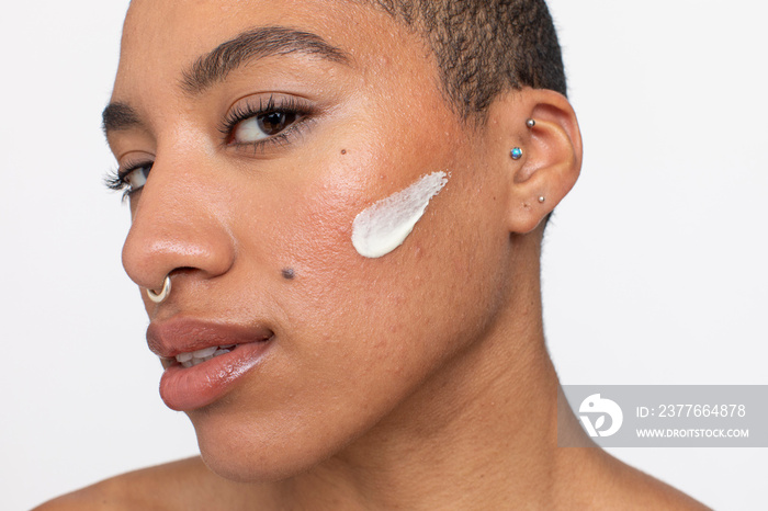 Studio portrait of woman face cream on cheek