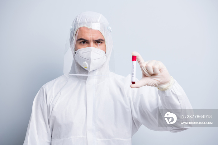 Photo of serious guy expert virology center clinic hold patient blood probe covid result wear face mask hood uniform suit plastic facial protection eyes nose isolated grey color background