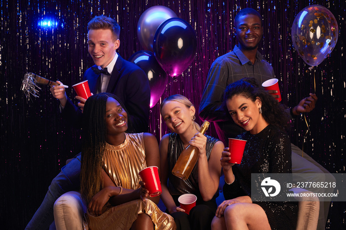 Multi-ethnic group of young people holding red cups while enjoying Birthday party or prom night, copy space