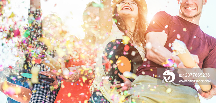 Happy friends having fun at festival party throwing confetti and dancing together