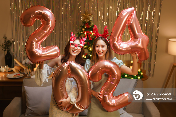 New Year celebration concept, Two beautiful women holding balloon pink gold number 2024 in party