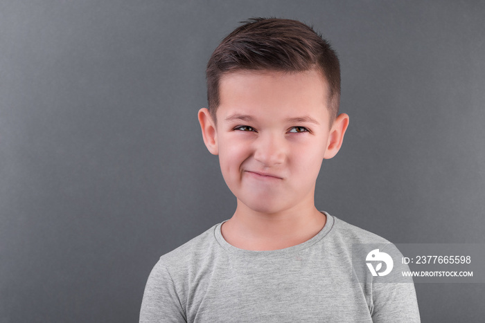 Handsome brunette boy doubt over grey background