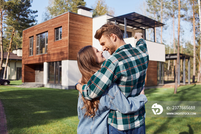 Happy man looking at his girlfriend against new home