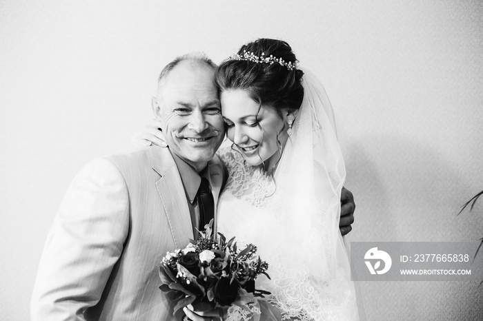 Happy father with his daughter, who gets married and holds a wedding bouquet in her hands