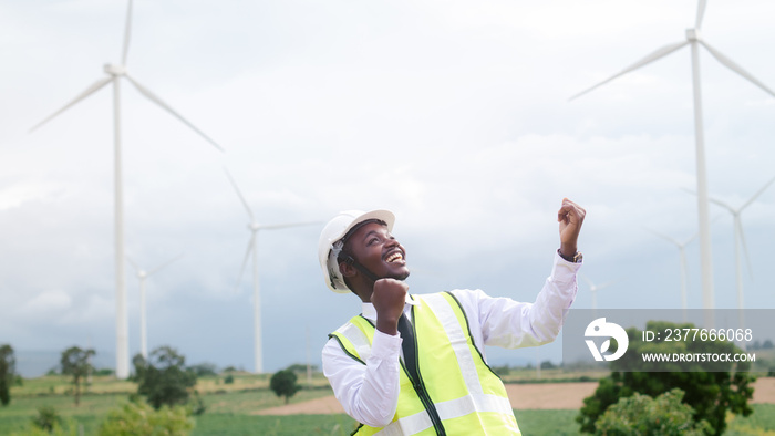 Success african engineer manager stand  front wind turbines generating electricity power station. .Concept of sustainability development by alternative energy