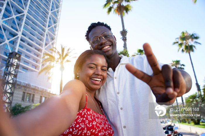 Selfie of a young black couple looking at camera smiling. Concept of vacation and relationship. African American couple having fun enjoying holidays