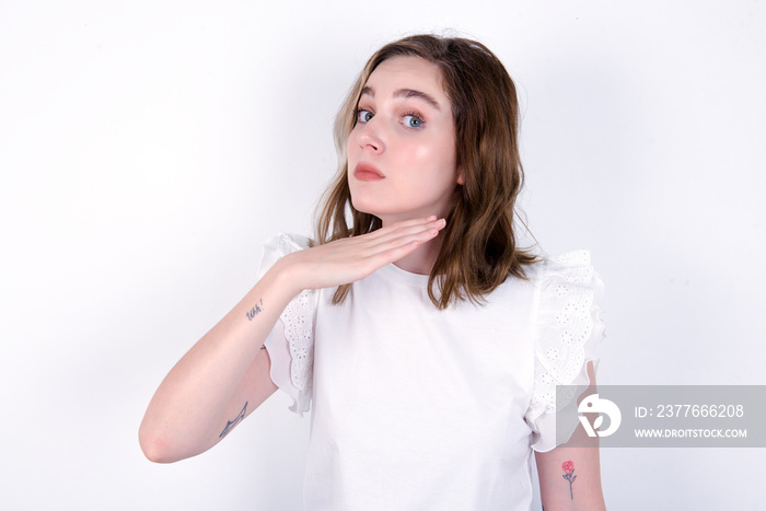 young caucasian woman wearing white T-shirt over white background cutting throat with hand as knife, threaten aggression with furious violence.