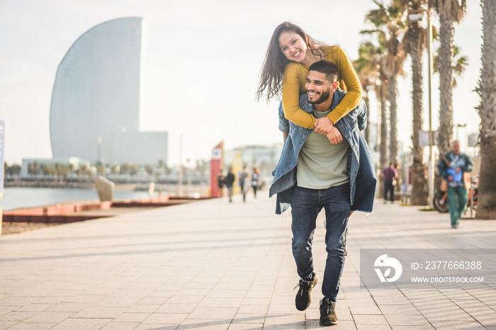 Happy couple having fun walking in Barcelona - Young people enjoying time together in Barceloneta - Travel, love, youth and lifestyle concept - Focus on faces