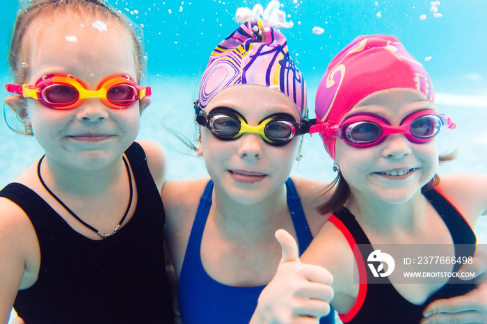 Underwater photo of young friends in swimming pool.