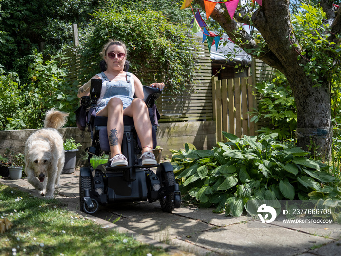 Woman in electric wheelchair with dog in back yard