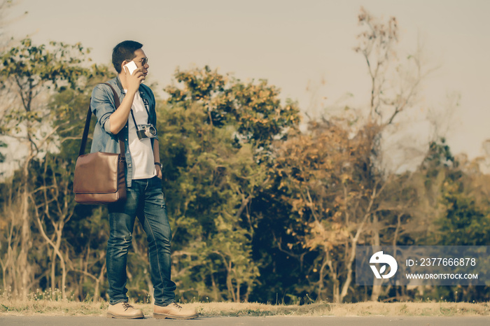 Man on smart phone and shoulder bag brown leather.