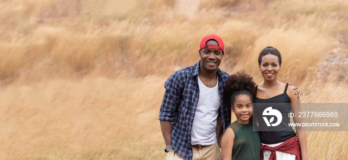 Happy Smiling African family enjoying and standing over meadow in spring summer together.