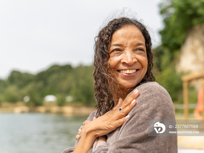 Portrait of smiling woman wrapped in towel by lake