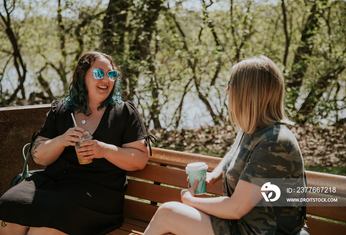 2 women sit on a bench talking and smiling