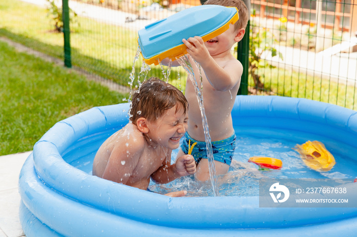 Two children with toys at swimming pool. Joyful kid playing in inflatable pool on the backyard. Little kids at swimming pool on sunny day. Healthy kids summer activity.