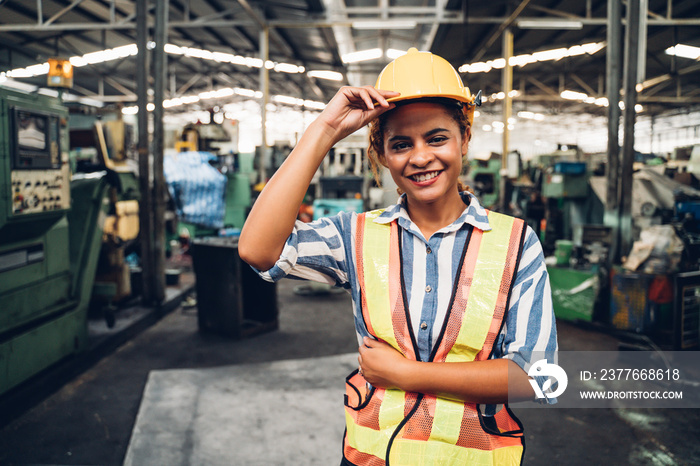 attractive young african woman smiling and working engineering in industry.Portrait of young female worker in the factory.Work at the Heavy Industry Manufacturing Facility concept.