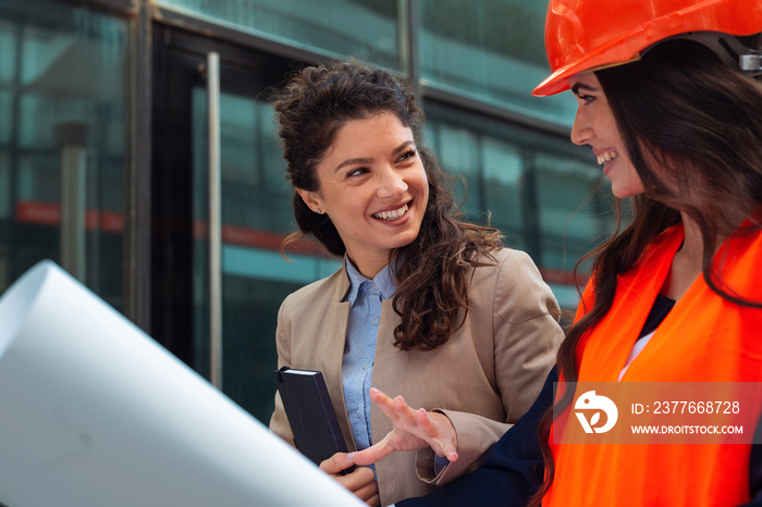 Engineers examining plans on construction site to client. Business woman looking at a plan.